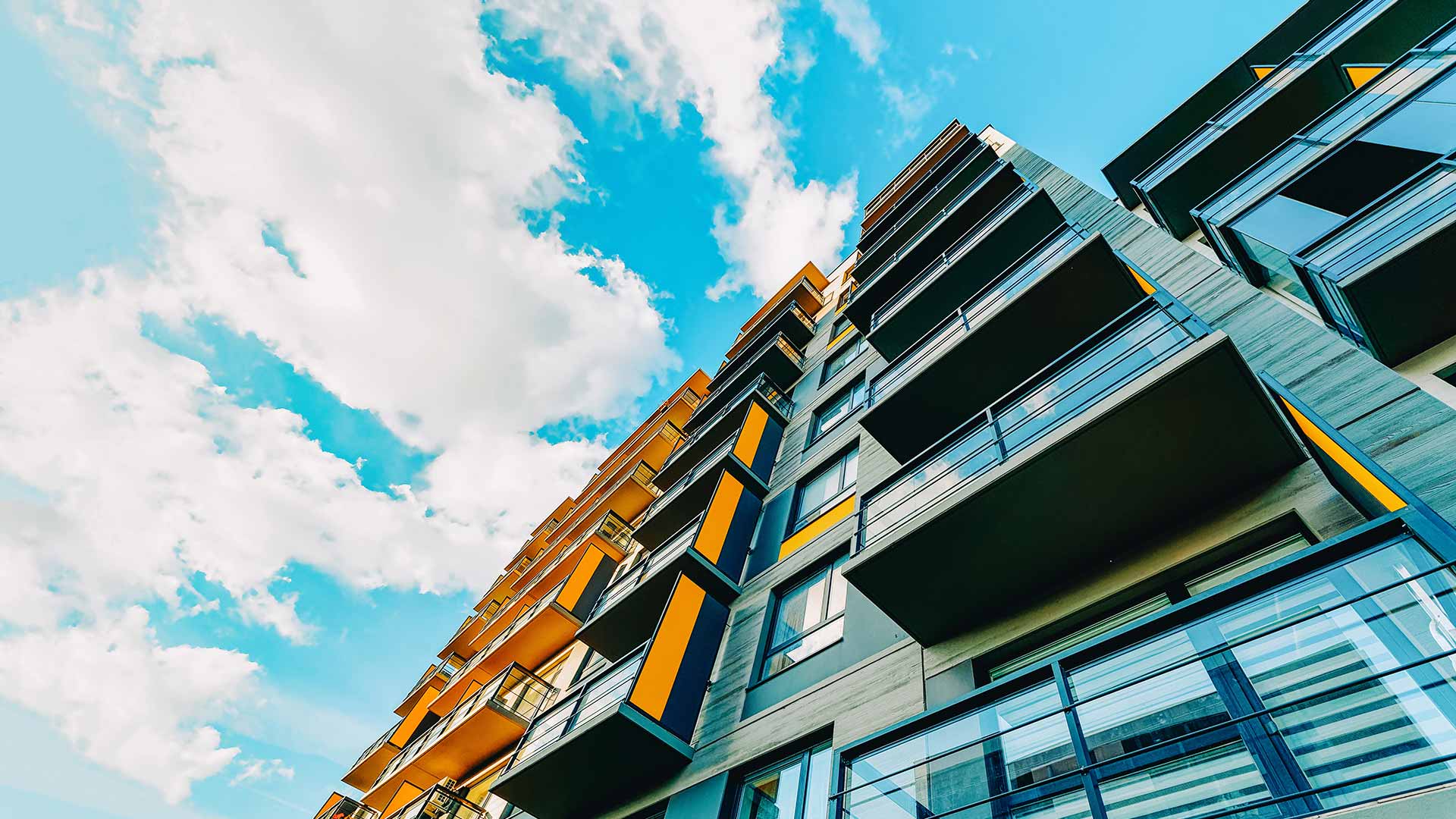 Modern condominium with balconies under a blue sky, reflecting the need for condo insurance and liability coverage.