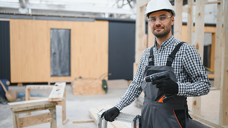 Worker in safety gear standing in a build under construction, highlighting insurance during construction needs.