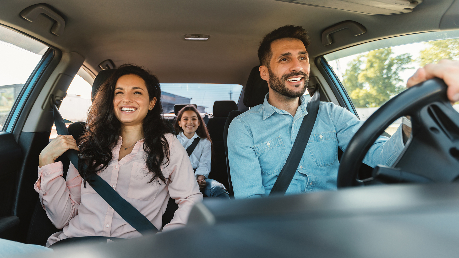 Family driving together in Oshawa, Ontario, smiling inside a car, representing safe and reliable auto insurance coverage